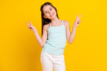 Photo of cheerful positive nice small girl make v-signs hello smile isolated on shine yellow color...
