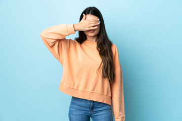 Young brunette girl over isolated blue background covering eyes by hands. Do not want to see...