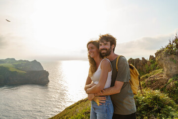 Couple in love hiking in a cliff. Horizontal view of backpackers sightseeing in holidays.