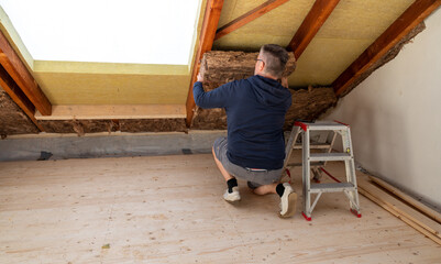 Craftsman putting insulation material to the attic..