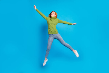 Fototapeta na wymiar Full length photo of carefree cheerful lady raise hand fist look empty space flying isolated on blue color background