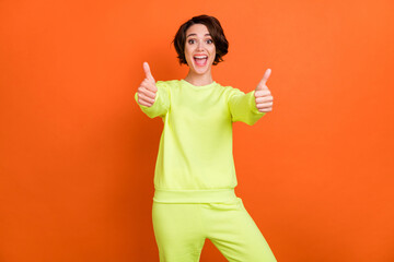 Photo of cheerful young happy woman show thumbs up good mood offer isolated on orange color background