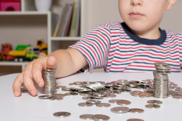 A child in glasses, a young businessman plays with coins and saves money.