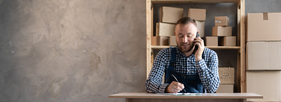 Male Salesman Confirming Orders From A Customer By Phone Makes Notes On Paper.