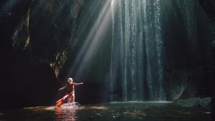 dancing woman in waterfall cave splashing water wearing beautiful dress enjoying nature dance feeling spiritual freedom 4k