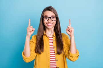 Photo of young woman happy positive smile point finger empty space direct way promo choose ad isolated over blue color background