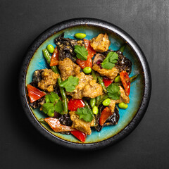 Udon stir-fry noodles bowl and vegetables on black stone background. Asian cuisine. Top view. Copy space.