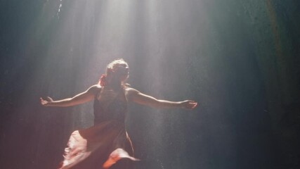 happy woman dancing in waterfall cave splashing water wearing beautiful dress enjoying nature dance feeling spiritual freedom 4k