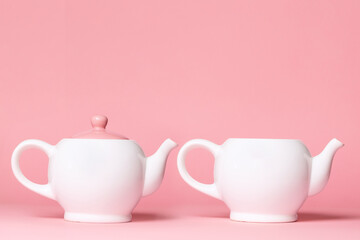 Two white porcelain teapots on a pink background. Copy space. The concept of Breast Cancer Awareness Month