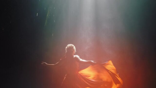 beautiful woman dancing in waterfall cave wearing beautiful dress enjoying dance feeling spiritual freedom 4k