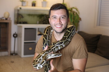 Man with large Burmese python at home 