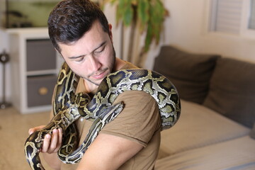 Man with large Burmese python at home 