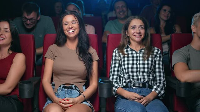 Laughing woman friends watching comedy film funny scene sitting on armchair audience at cinema