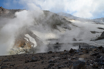 a valley of fumaroles with an eruption of water vapor and sulfur. Climbing the Mutnovsky volcano. Kamchatka Peninsula.