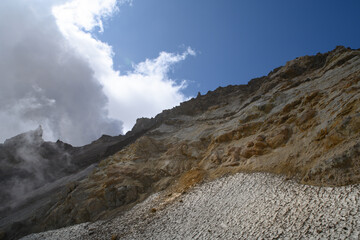 the steep slope of the volcano with stone scree and preserved snow. Mutnovsky volcano. Kamchatka Peninsula