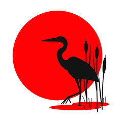 Silhouette of a heron in the reeds against the background of the red sun