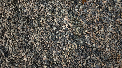 Street covered pebbles on sea coast. Rough uneven little bit fraction grunge marble terrace pathway. Summer smooth washed rustic stone. Scratched shabby grungy granite old rock for 3d seaside design