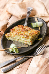 part de gratin de ravioles au saumon et courgettes sur assiette métallique noire design