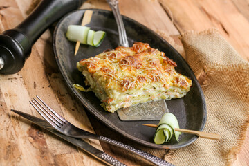 part de gratin de ravioles au saumon et courgettes sur assiette métallique noire design