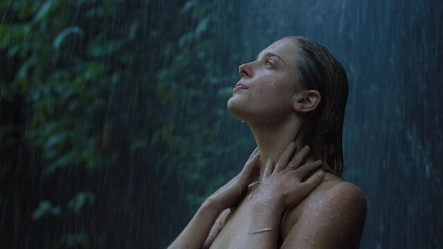 sexy woman under waterfall wearing bikini enjoying refreshing water splashing on body in tropical jungle 4k