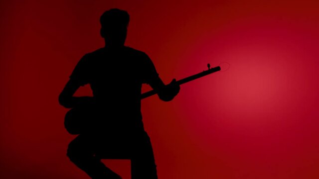 Silhouette man playing Kopuz which is a string instrument named Baglama with three strings on a red background.