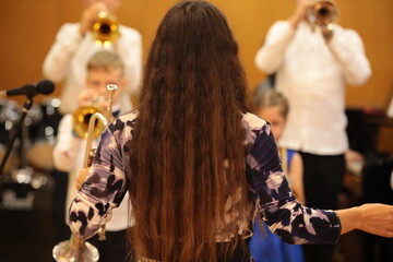 Music teacher mentor conductor of a children's orchestra in a classroom with students boys and a...