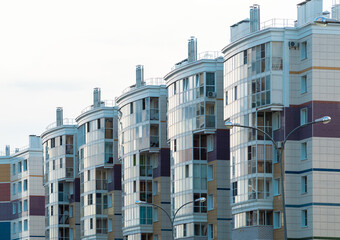 Close up of glazed balconies and windows of a new building in a residential area of the city, the reflection of the sky in a glass wall.