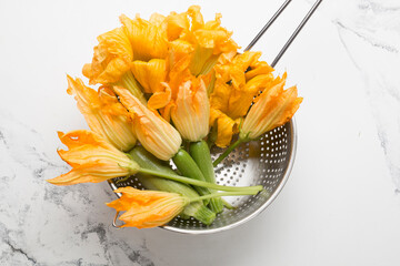 Zucchini and zucchini flowers on white marble background
