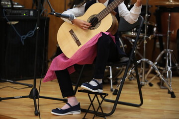Naklejka premium Child teenage girl musician playing the guitar young artist performing at school concert on stage