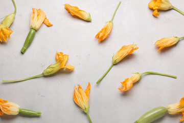 Fresh yellow zucchini flowers on a light background. A lot of zucchini on a light background.
