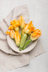 Zucchini and zucchini flowers in a plate on white marble background
