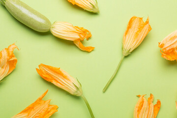 Fresh bright zucchini and zucchini flowers on green background
