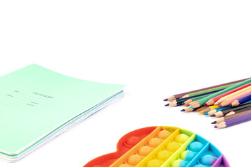 Naklejka premium School items. Notebooks, pencils for drawing and silicone toy popit on white background. Concept of education, back to school, creativity and learning. Copy space.