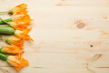 Fresh yellow zucchini flowers on a light wooden background. Lots of zucchini on a wooden...