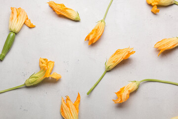 Fresh yellow zucchini flowers on a light background. A lot of zucchini on a light background.
