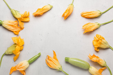 Fresh yellow zucchini flowers on a light background. A lot of zucchini on a light background.
