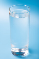 Glass of pure cold water on a blue background.