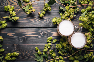Two mugs of frothy beer on the wooden table flat lay background with copy space.