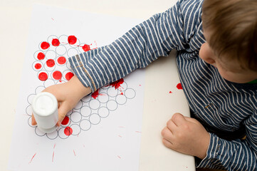 fine motor skills, hand coordination. little toddler making stamps on paper with heart shape print....