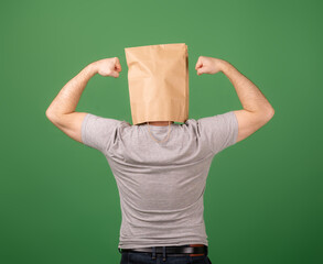 A man with a bag on his head, a dazed head demonstrates strength against a green background....