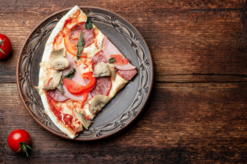 Pizza with ham and bacon, mushrooms on a clay plate on a brown wooden background.