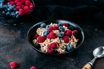Oatmeal with raspberries and blueberries in a black plate