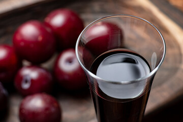 Plum red wine on a dark wooden background. Glass with red wine close up.