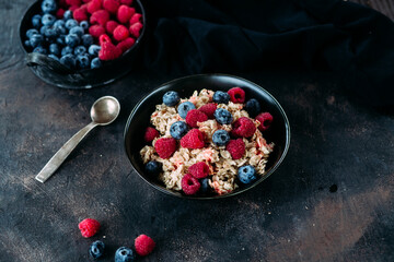 Oatmeal with raspberries and blueberries in a black plate