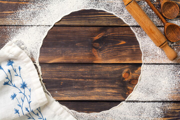 Fototapeta na wymiar Flour scattered in the form of a circle, rolling pin and white linen napkin on an old wooden background. Place for text. Background for baking