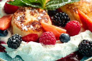 Closeup on sweet cottage cheese pancakes with berries and cream
