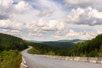 The highway winds between the mountains, a beautiful landscape with clouds in the distance