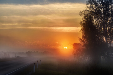 Sunrise in the early summer morning on the highway, light fog