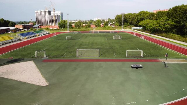 A new stadium in the area of new urban buildings. Football gates and a running track. A new neighborhood. Modern sports facilities in Russia.