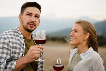 Smiling couple toasting wine glasses outdoors in mountains